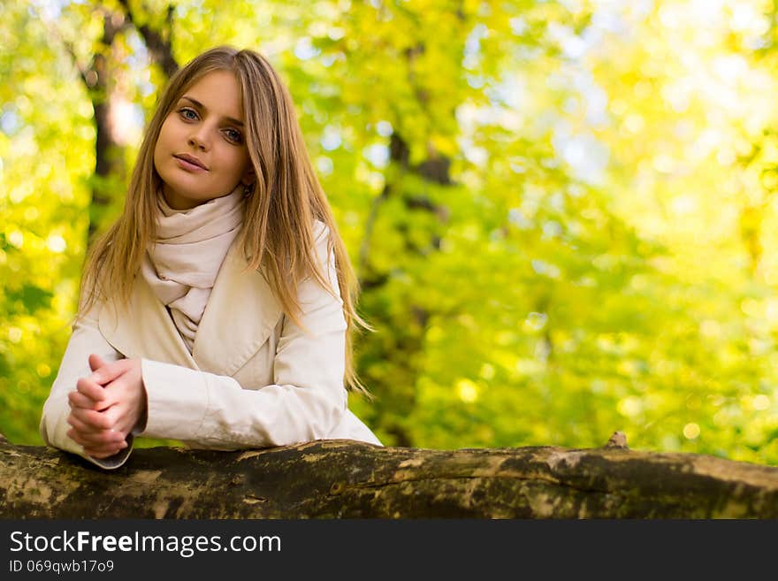 Portrait of a girl on a background autumn forest. A light raincoat. Black sweater. Portrait of a girl on a background autumn forest. A light raincoat. Black sweater.