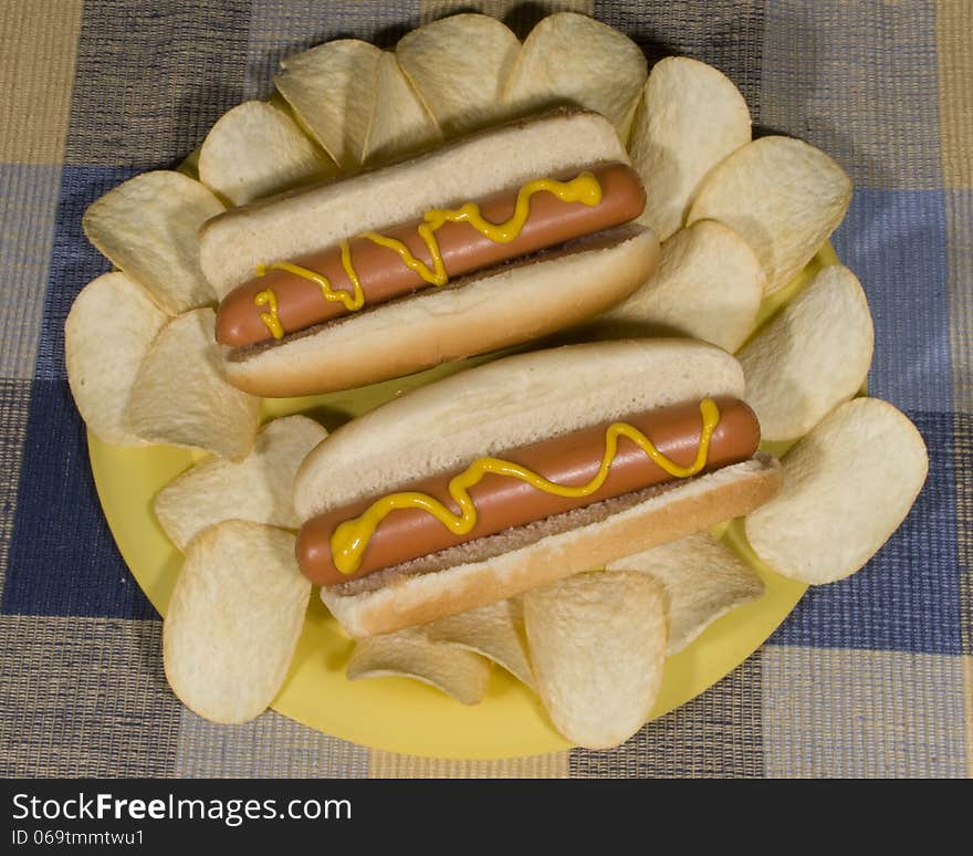 Hot dogs on a plate with chips