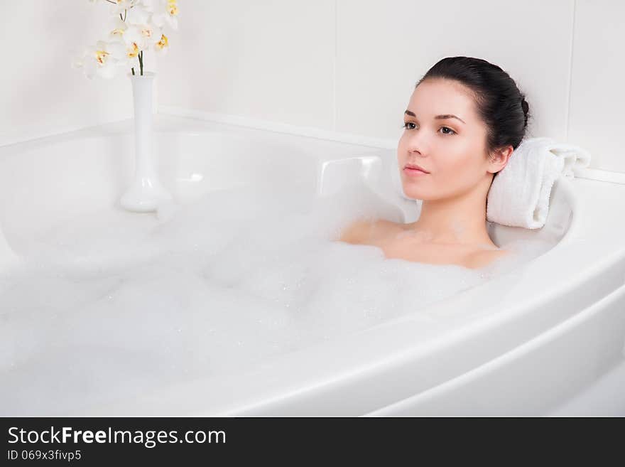 Beautiful young woman takes bubble bath