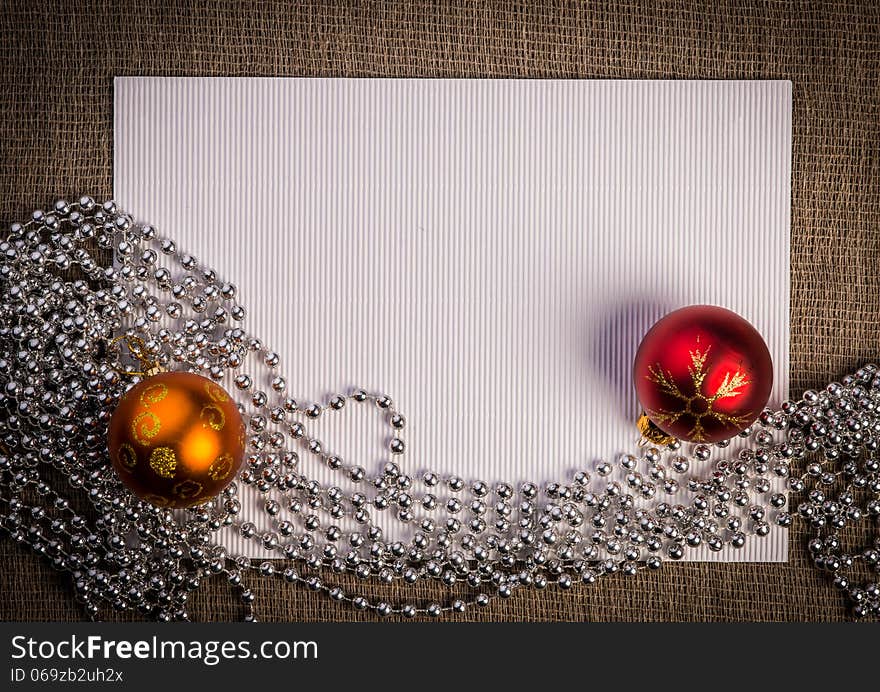 Horizontal blank greeting card. Light brown color linen background, claret paper, two pine cones and silver, golden color beads composition. Horizontal blank greeting card. Light brown color linen background, claret paper, two pine cones and silver, golden color beads composition.