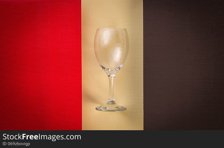 Empty wineglass reflecting light, over colorful textured background. Empty wineglass reflecting light, over colorful textured background.