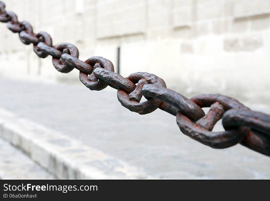 Old long rusty chain on gray building wall background. Old long rusty chain on gray building wall background