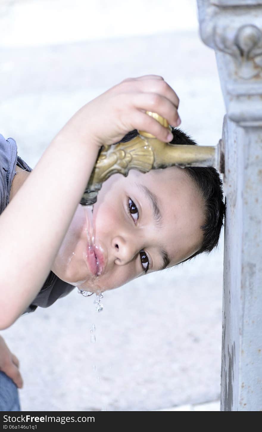 Child drinks water in a fountain in a park. Child drinks water in a fountain in a park.