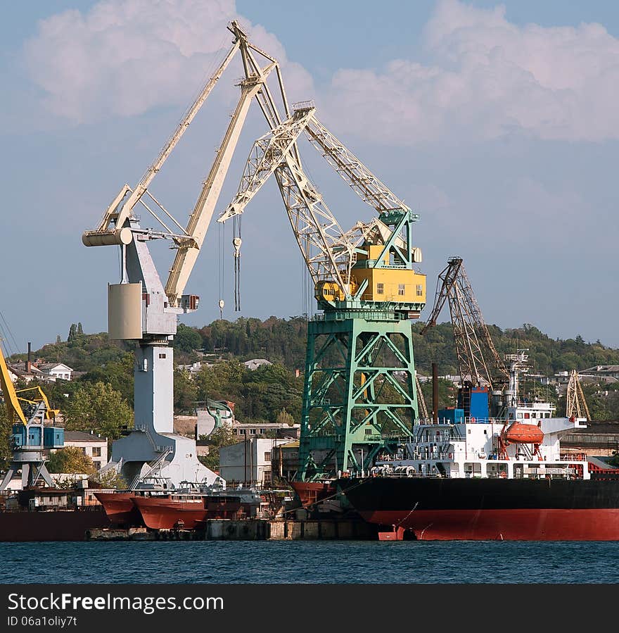 Industrial landscape - sea port with ships and cranes. Construction works in the sea at the offshore platform. Skyline with marine crane platform and cargo ship. Cargo seaport with harbor crane. Industrial equipment of the sea port - wharf cranes. Industrial landscape - sea port with ships and cranes. Construction works in the sea at the offshore platform. Skyline with marine crane platform and cargo ship. Cargo seaport with harbor crane. Industrial equipment of the sea port - wharf cranes.