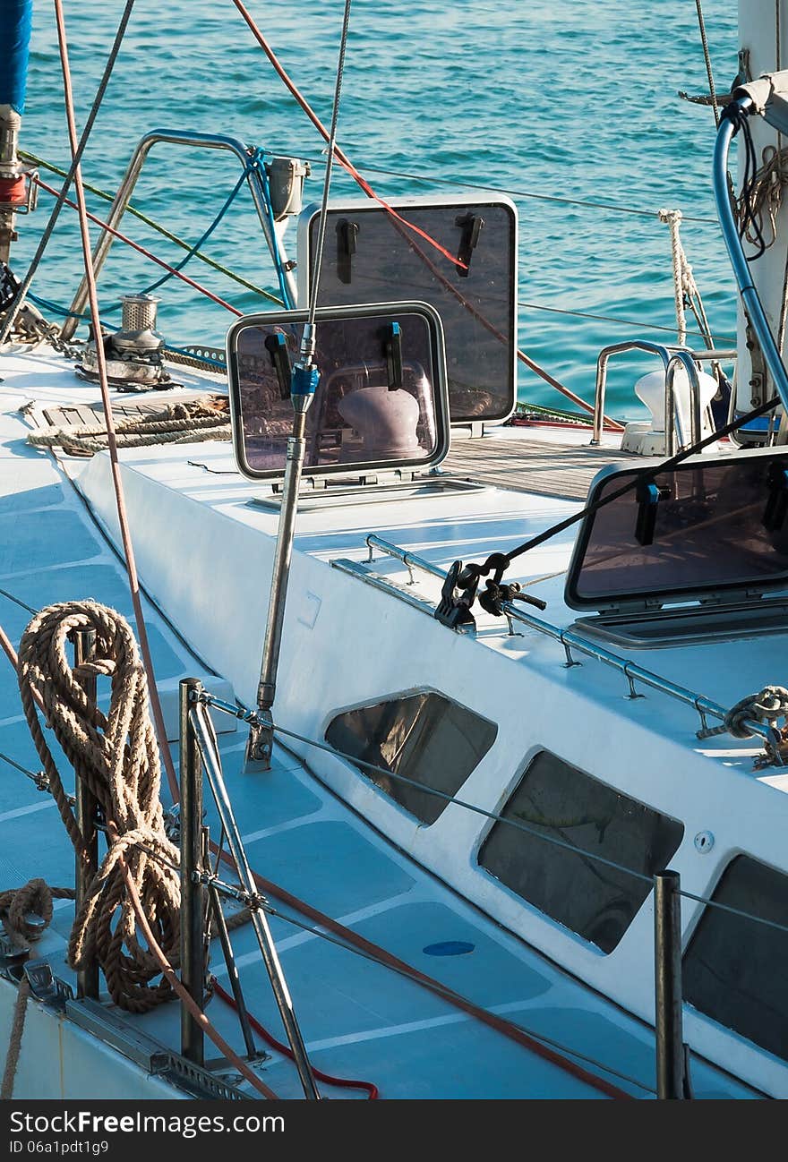 Nautical details on ship deck with ropes and marine tools equipping. Ropes on classic sailboat - tackles on the yacht. Cruising yacht exterior - up of the deck, captain's cabin, portholes and mast.