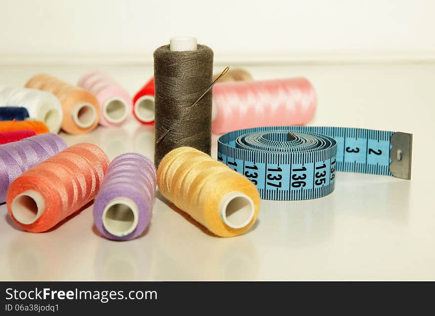 Colorful spools of thread, a needle to inject into the coil and measuring tape