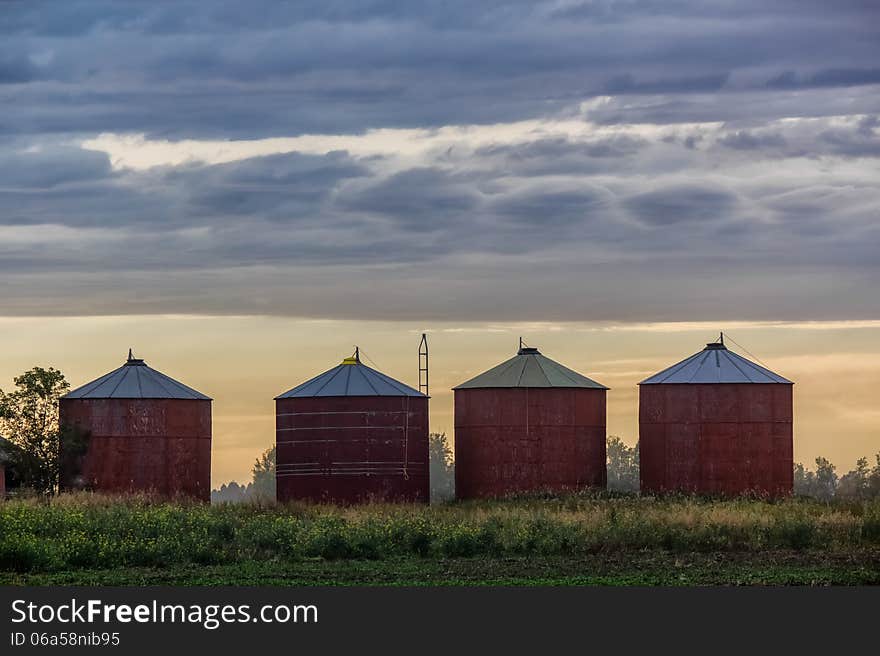 Grain bins against a setting sun