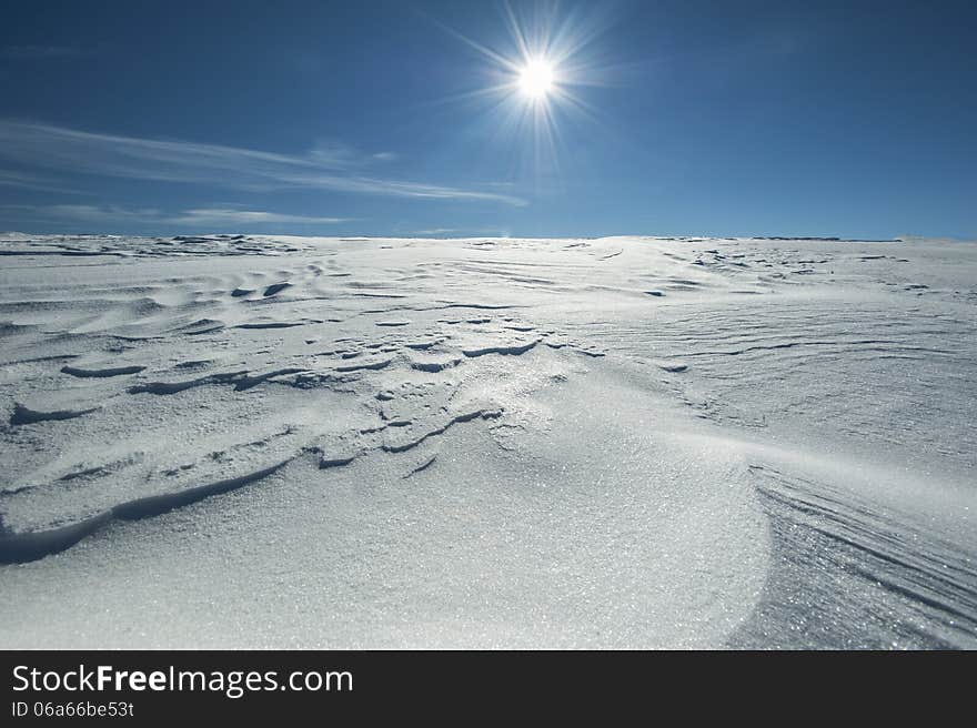 Winter alpine scenery with snow dunes and frozen snow