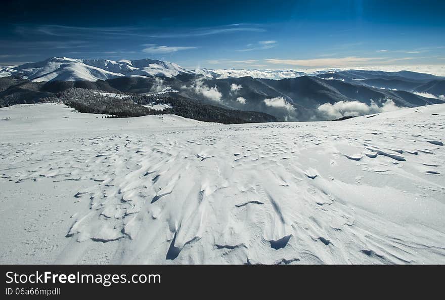 Winter alpine scenery with snow dunes and frozen snow