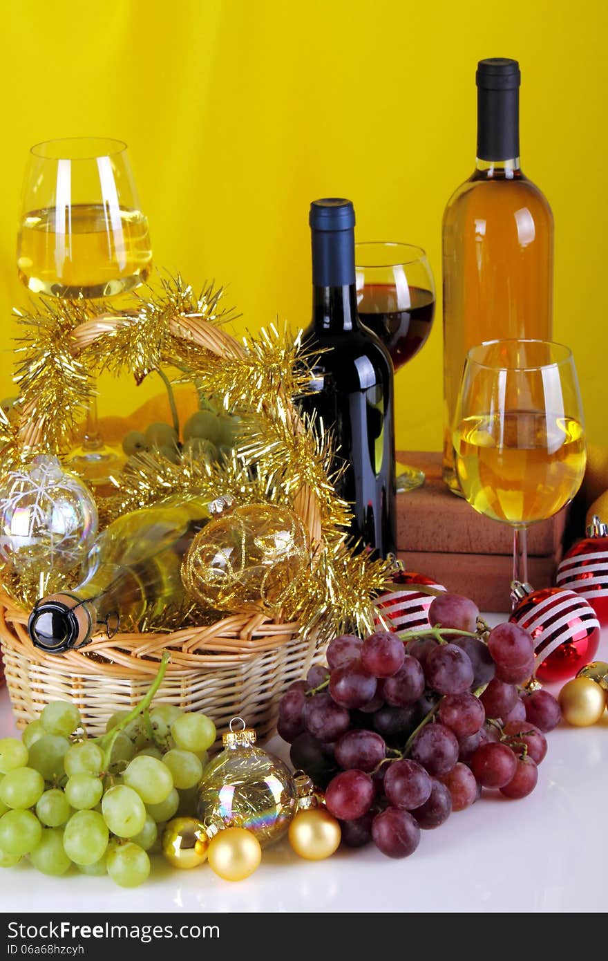 Bottles of wine with grapes and Christmas decorations on a white top and yellow cloth background. Bottles of wine with grapes and Christmas decorations on a white top and yellow cloth background