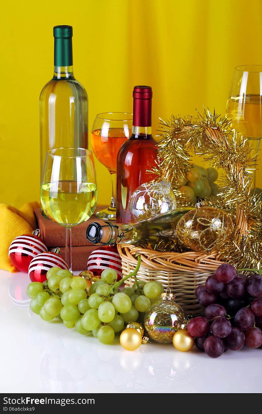 Bottles of wine with grapes and Christmas decorations on a white top and yellow cloth background