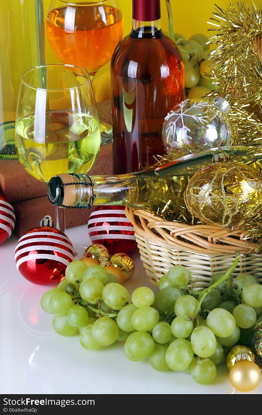 Bottles of wine with grapes and Christmas decorations on a white top and yellow cloth background