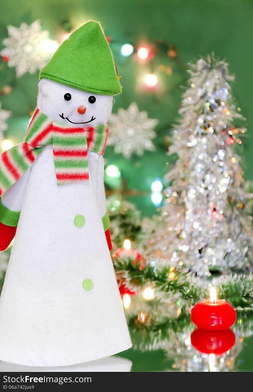 Christmas new year decoration with a toy - snowman, candles and lights of garlands on a green background. Christmas new year decoration with a toy - snowman, candles and lights of garlands on a green background