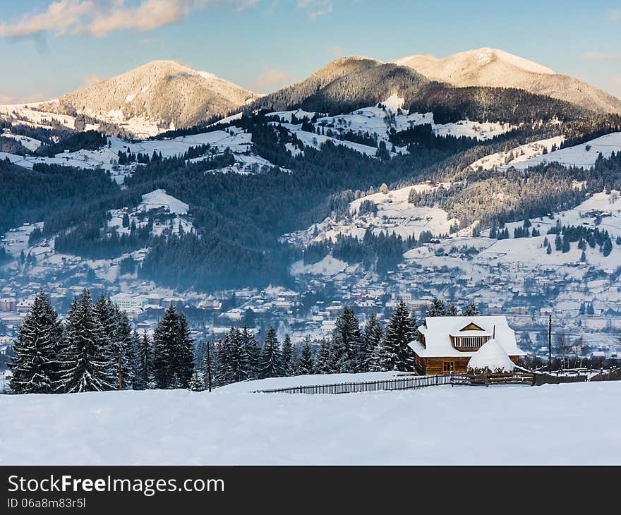 Winter landscape with a lonely cottage on a background of mountains