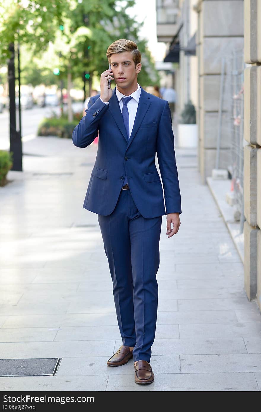 Attractive young businessman on the phone in urban background