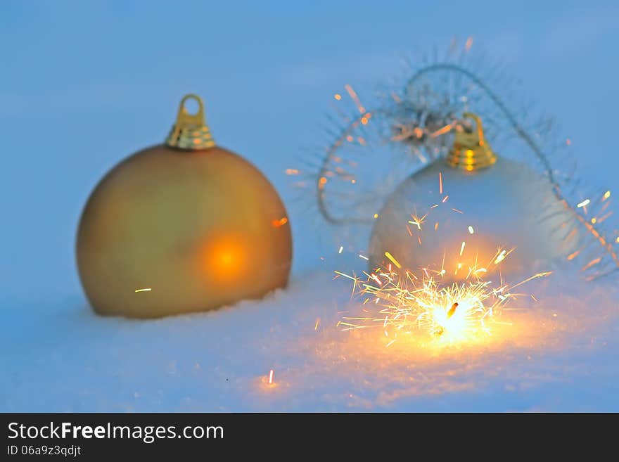 Bengal light, golden and silver christmas balls in snow. Bengal light, golden and silver christmas balls in snow