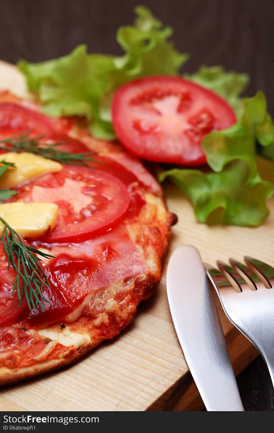 Closeup of freshness hot pizza on wooden plate near fork and knife. Closeup of freshness hot pizza on wooden plate near fork and knife