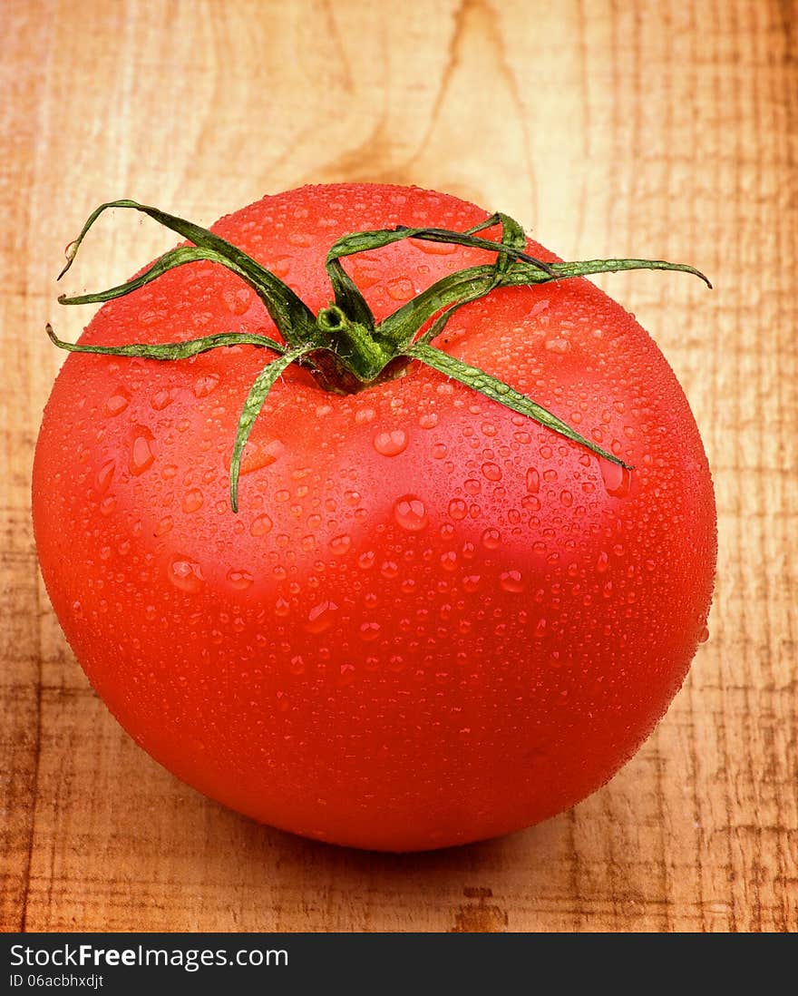 Big Ripe Tomato with Water Drops closeup on Rustic Wooden background