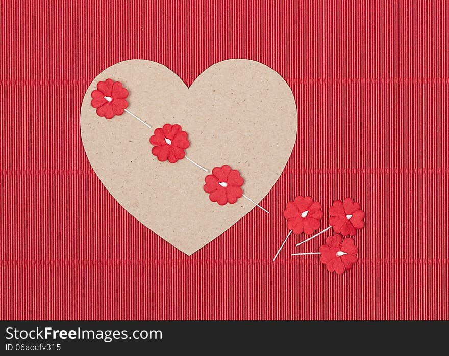 Cardboard heart with paper flowers on red background