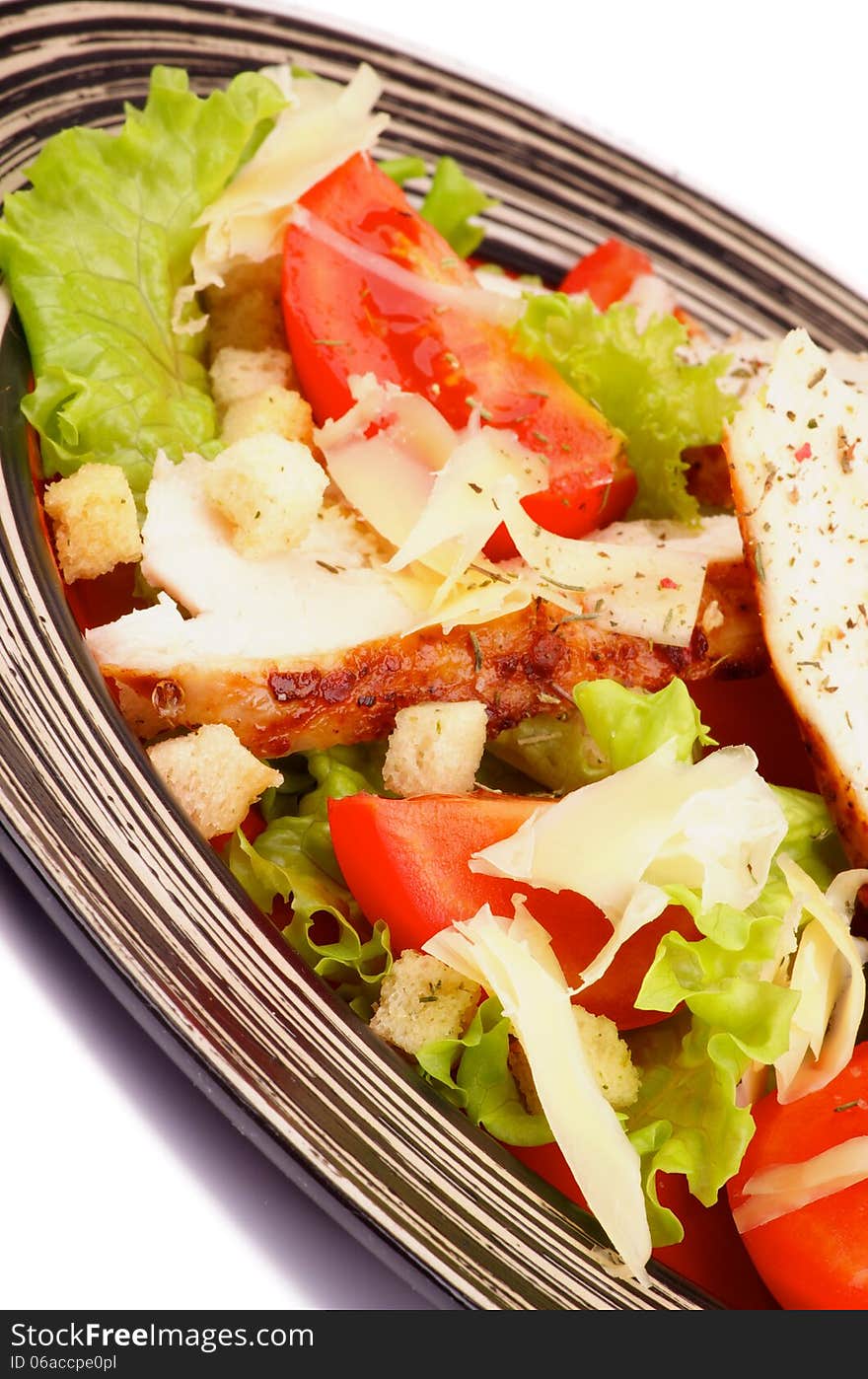 Caesar Salad with Grilled Chicken Breast, Garlic Crouton, Lettuce, Tomatoes and Grated Parmesan Cheese closeup on Striped Plate