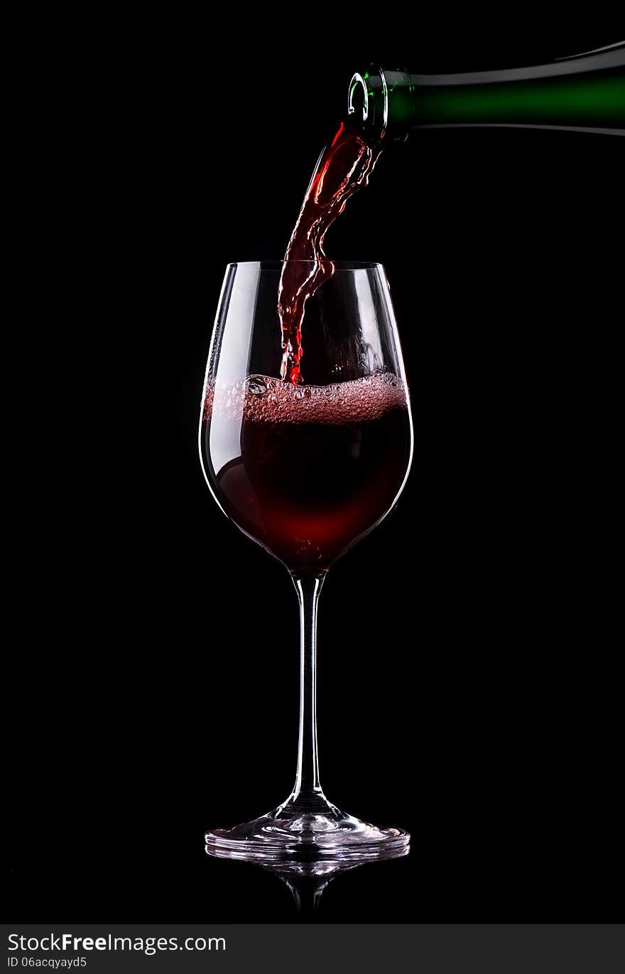 Red wine being poured into a glass on a black background