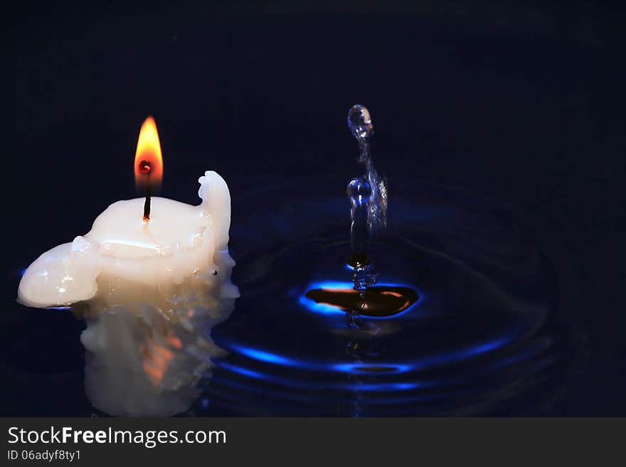 Lighting candle on dark splashing water surface. Lighting candle on dark splashing water surface