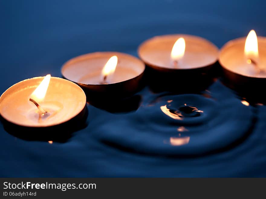 Few lighting candles on dark splashing water surface. Few lighting candles on dark splashing water surface