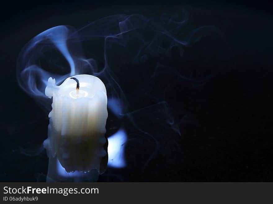 Extinguished candle with smoke on dark background