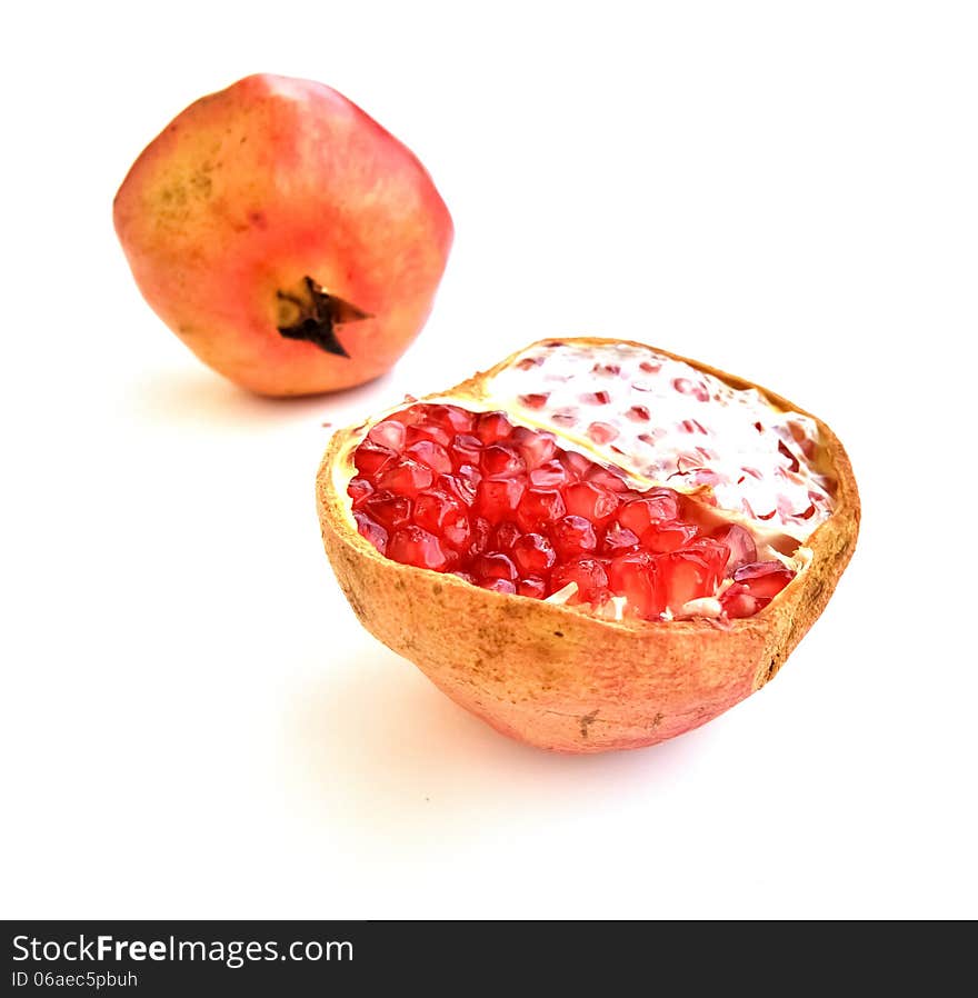 An open pomegranate fruit with a blurred full fruit in the background. An open pomegranate fruit with a blurred full fruit in the background