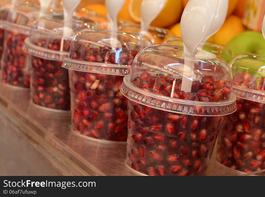 Grains of pomegranate in glass at market stand