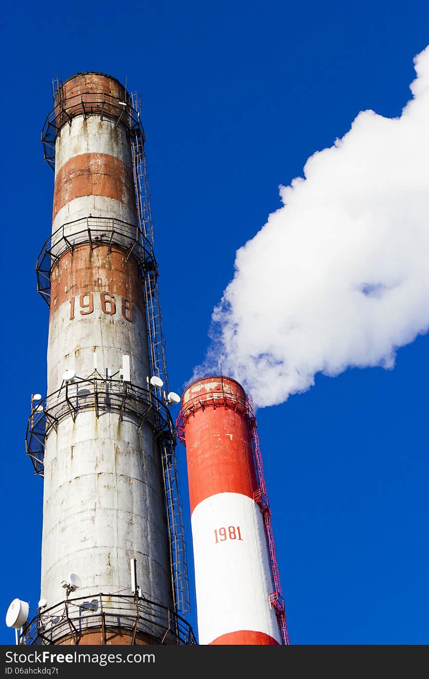 Pipes of power plant smoke against the bright blue sky. Pipes of power plant smoke against the bright blue sky