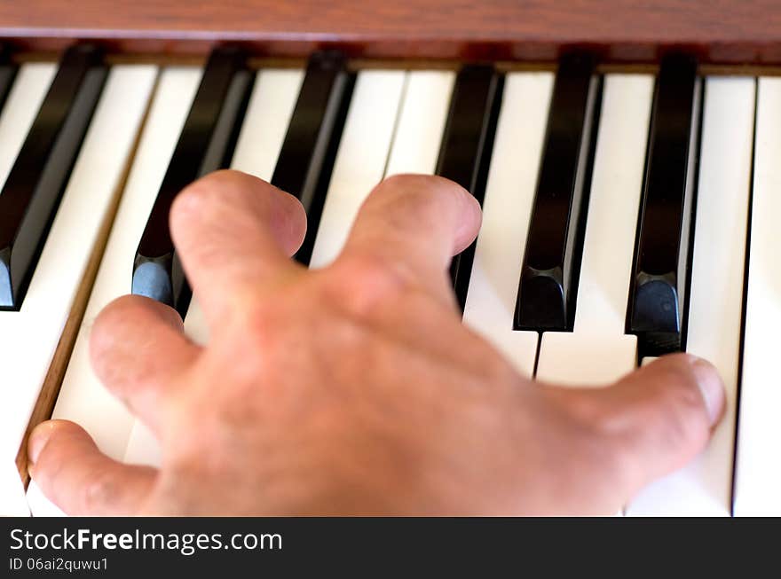 Piano player hand plays the piano.