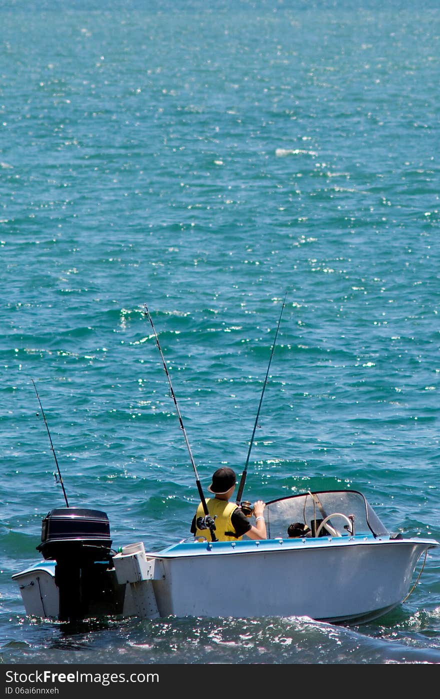 Fishing boat with fisherman holding rod in action.