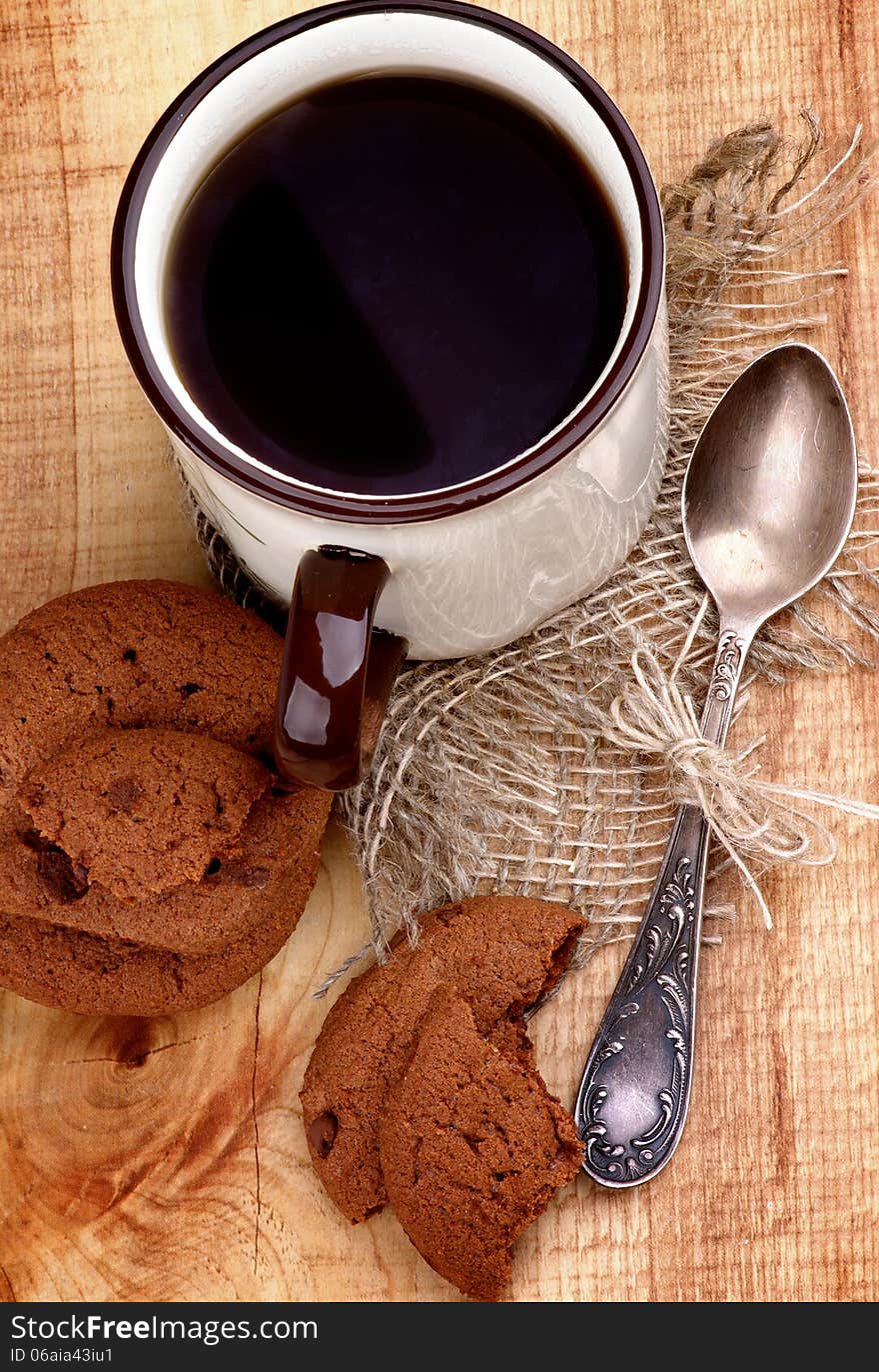 Arrangement of Rustic Cup of Black Tea with Chocolate Chip Cookies and Tea Spoon closeup on Wooden background. Top View. Arrangement of Rustic Cup of Black Tea with Chocolate Chip Cookies and Tea Spoon closeup on Wooden background. Top View