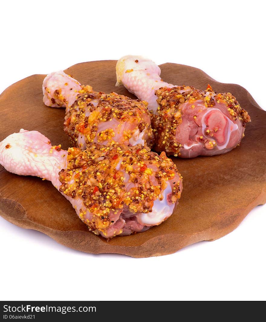 Three Raw Chicken Drumsticks Marinated with Whole Grain Mustard closeup on Wooden Plate on white background. Three Raw Chicken Drumsticks Marinated with Whole Grain Mustard closeup on Wooden Plate on white background