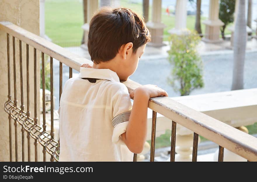 Little boy standing alone at balcony rimlight