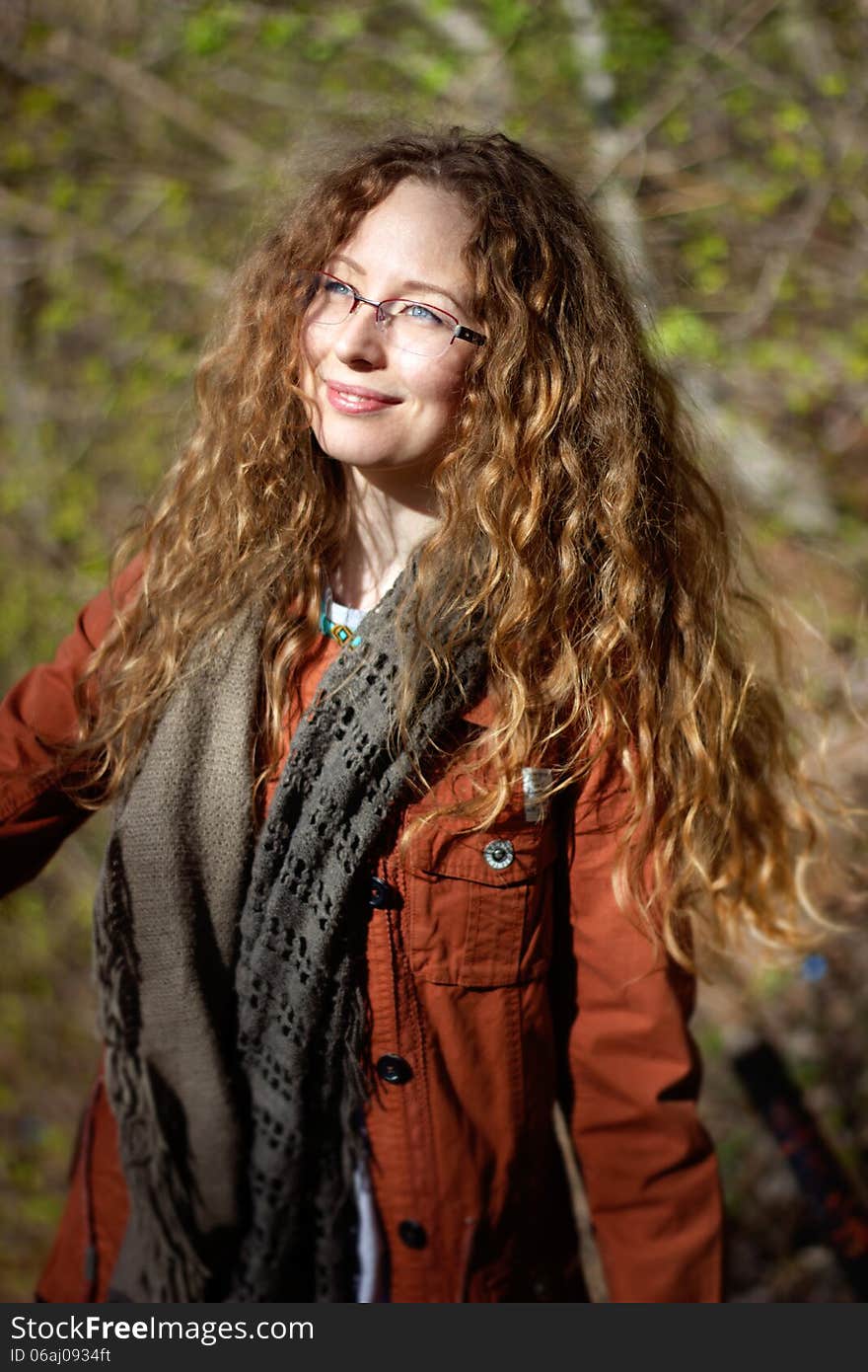 Smiling Woman With Glasses And Blonde Curly Hair On Sunny Forest Background