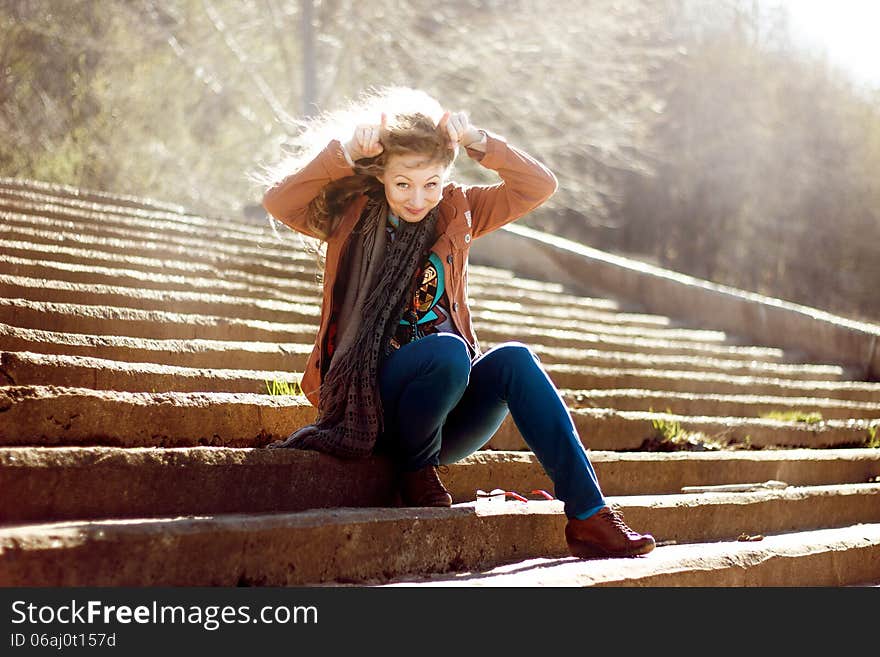 Funny Woman With Blonde Curly Hair On Stairs Background