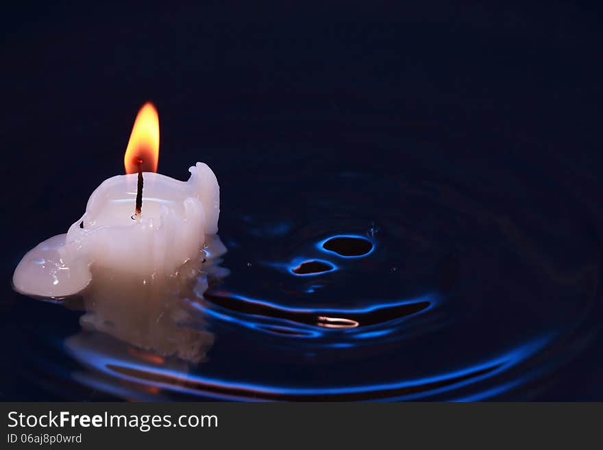 One lighting candle on dark splashing water surface. One lighting candle on dark splashing water surface