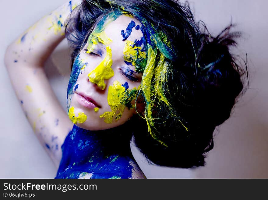 Beauty/fashion portrait of woman painted blue and yellow on black background