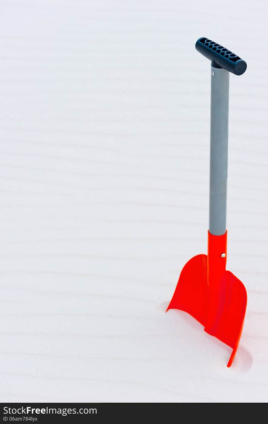 Vertical shot of an orange shovel in the sand