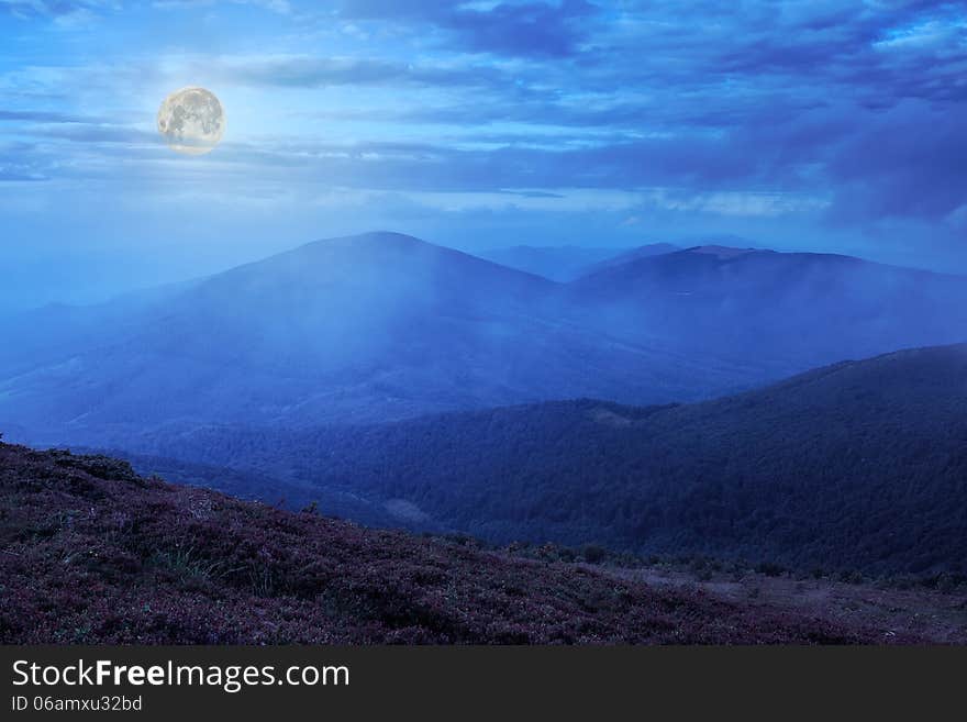 Mountain landscape. valley with stones on the hillside. forest on the mountain under the beam of light falls on a clearing at the top of the hill at midnight. Mountain landscape. valley with stones on the hillside. forest on the mountain under the beam of light falls on a clearing at the top of the hill at midnight