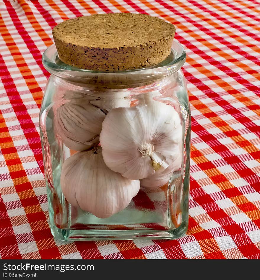 Garlic bulbs in glass jar on a checkered table-cloth