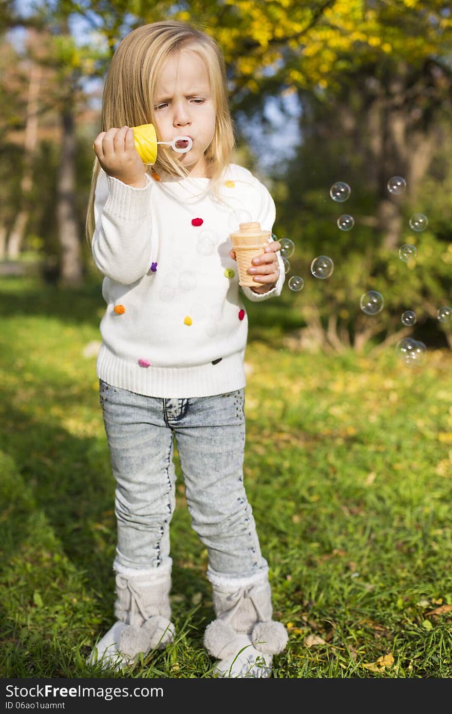 Funny little girl with soap bubbles in park