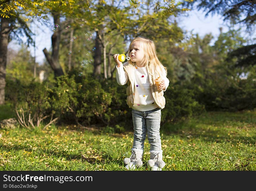 Funny little girl with soap bubbles in park