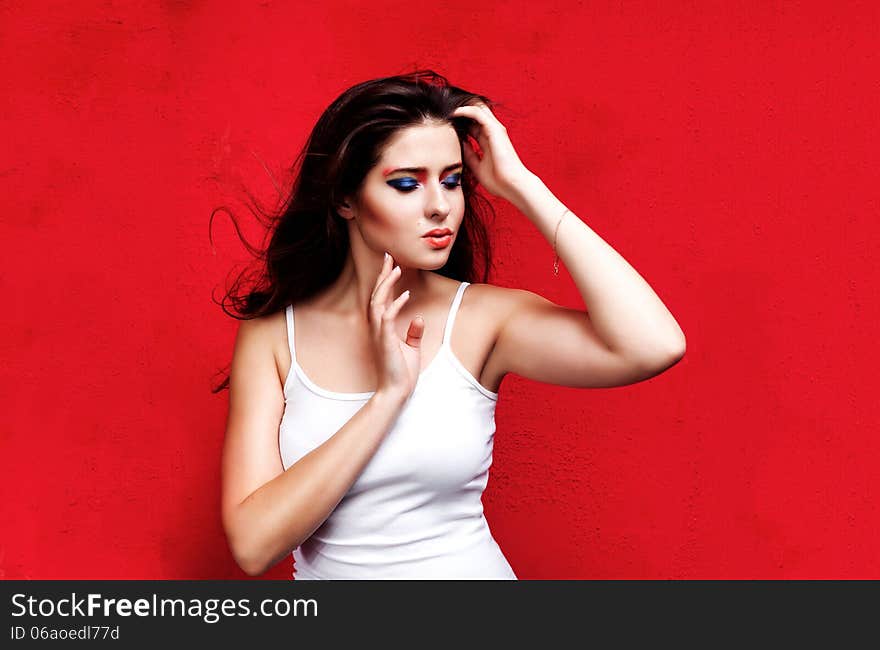 Beauty portrait of woman with colorful makeup on red backround