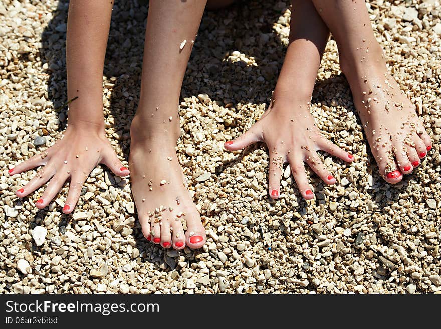 Manicure on hands and feet on beach sand background