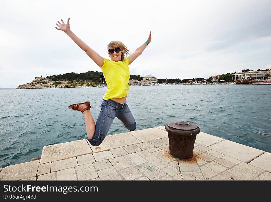 Young cheerful woman jumping on the pier