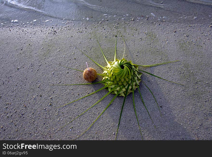 One ccoconuts and sun hat knees out of palm leaves on sandy sea shore of tropical island. One ccoconuts and sun hat knees out of palm leaves on sandy sea shore of tropical island.