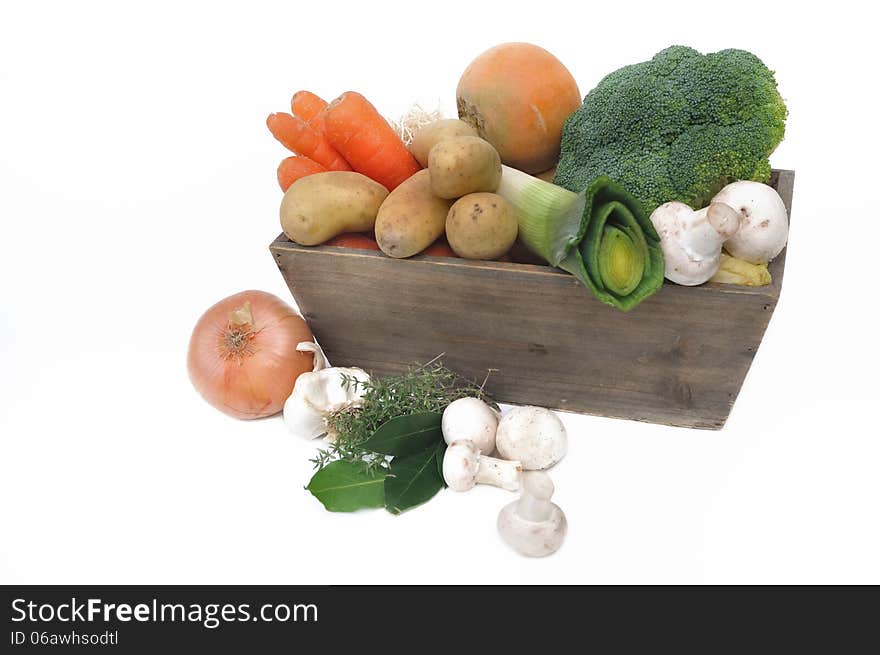 Several seasonal vegetables in a wooden basket on white background